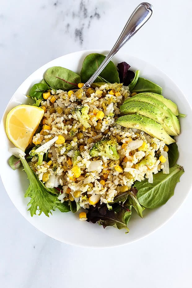 This Healthy Veggie Rice Bowl has corn, peas and broccoli mixed with brown rice over a bed of lettuce and a side of avocado! It is vegan and gluten free and perfect for a light healthy lunch. /TwoRaspberries.com