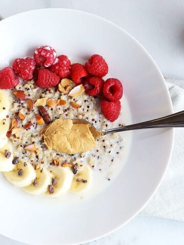 This 7 ingredient superfood quinoa breakfast bowl is SO quick and easy to make and PERFECT for a grab and go breakfast! Topped with raspberries, bananas, nuts and cacao nibs! / TwoRaspberries.com