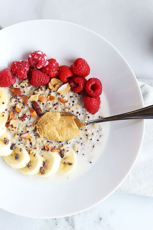 This 7 ingredient superfood quinoa breakfast bowl is SO quick and easy to make and PERFECT for a grab and go breakfast! Topped with raspberries, bananas, nuts and cacao nibs! / TwoRaspberries.com