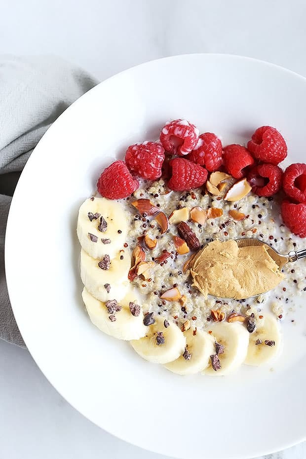 This 7 ingredient superfood quinoa breakfast bowl is SO quick and easy to make and PERFECT for a grab and go breakfast! Topped with raspberries, bananas, nuts and cacao nibs! / TwoRaspberries.com