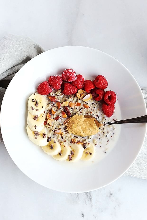 This 7 ingredient superfood quinoa breakfast bowl is SO quick and easy to make and PERFECT for a grab and go breakfast! Topped with raspberries, bananas, nuts and cacao nibs! / TwoRaspberries.com