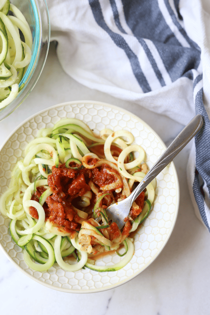 zucchini noodles topped with spaghetti sauce for an easy healthy plants based meal