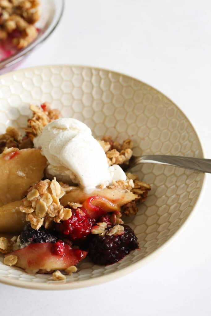 apple and blackberry crumble topped with vanilla ice cream