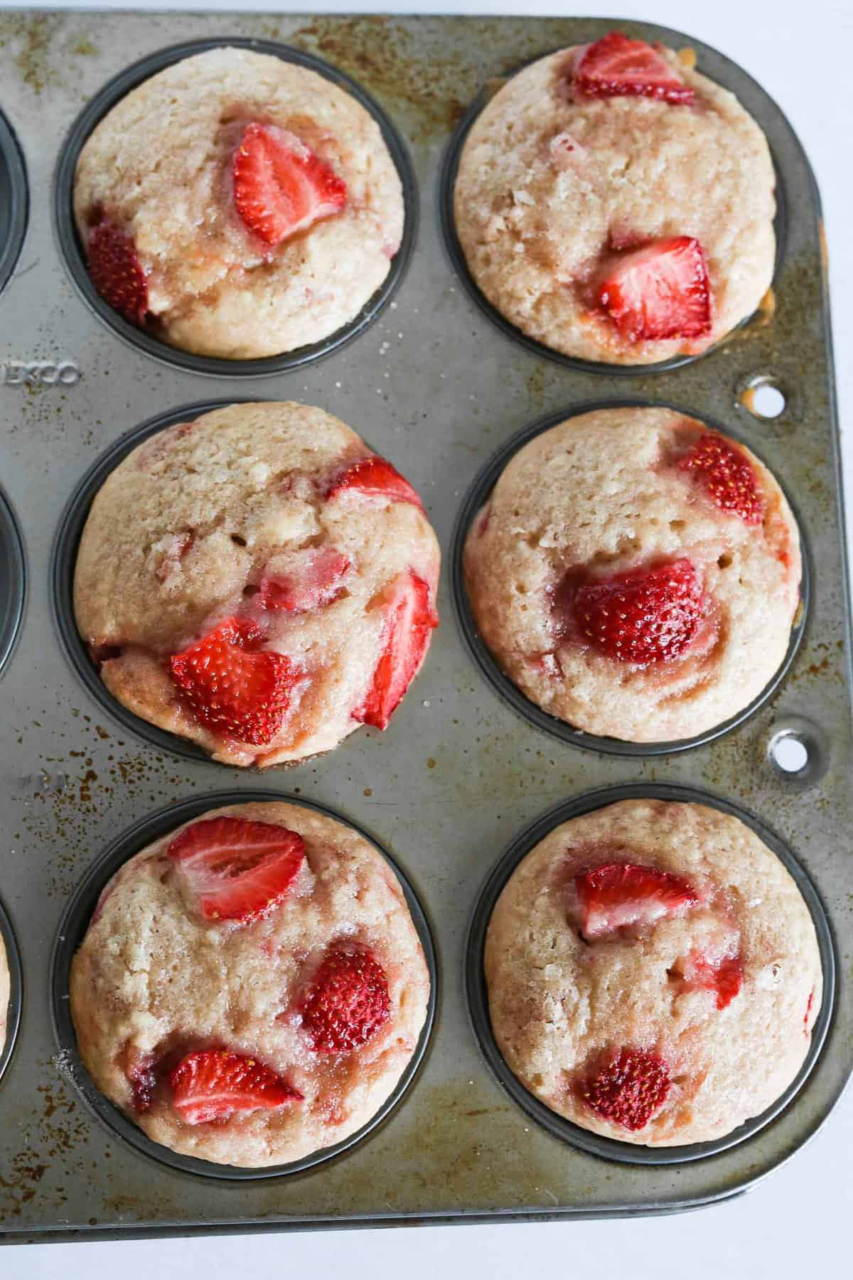Freshly baked vegan strawberry muffins in muffin tin.