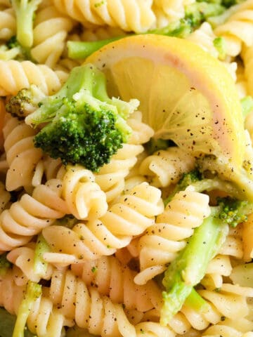 Lemon broccoli pasta in a bowl with a lemon wedge on top.