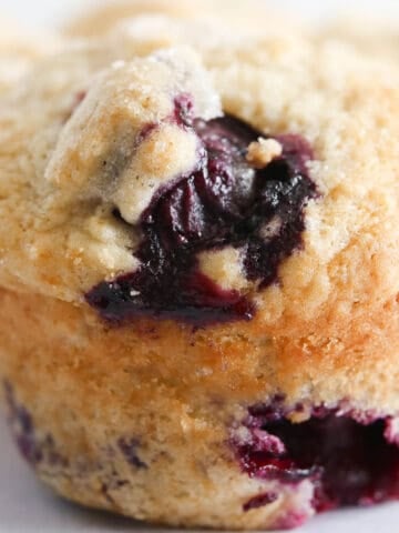 A vegan muffin with blueberries in the front and a curved done.