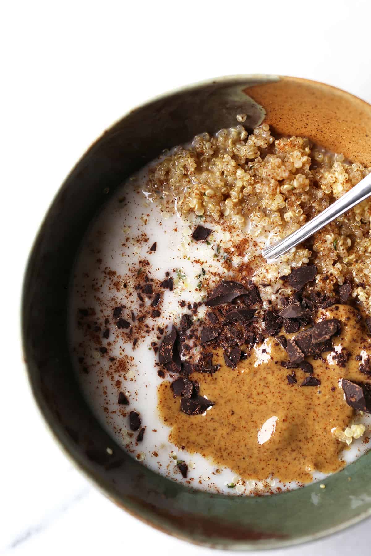 Quinoa breakfast bowl topped with chocolate and nut butter.