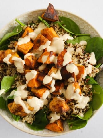 Spinach sweet potato quinoa salad in a bowl with a fork digging in.