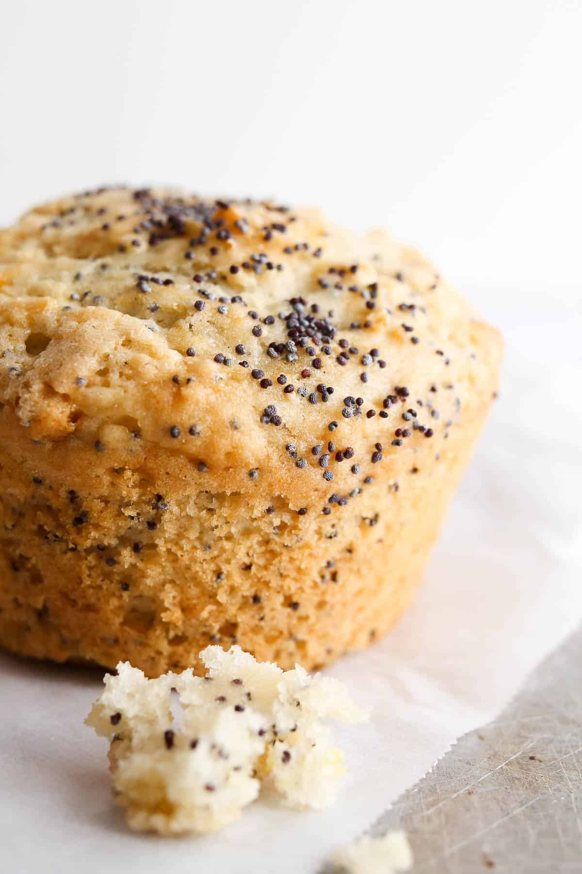 A lemon poppy seed muffin sitting on the table on a piece of parchment paper.