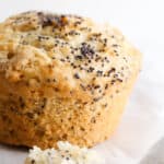 A lemon poppy seed muffin sitting on the table on a piece of parchment paper.