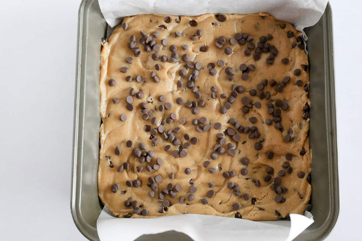 Chocolate Chip Cookie Bars in lined baking dish ready to be baked.