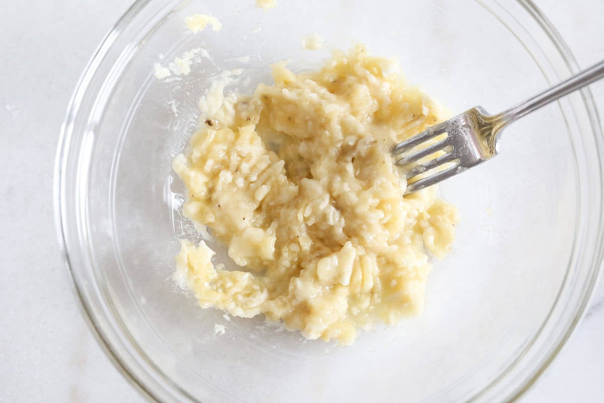 Glass bowl with a fork mashing banana.