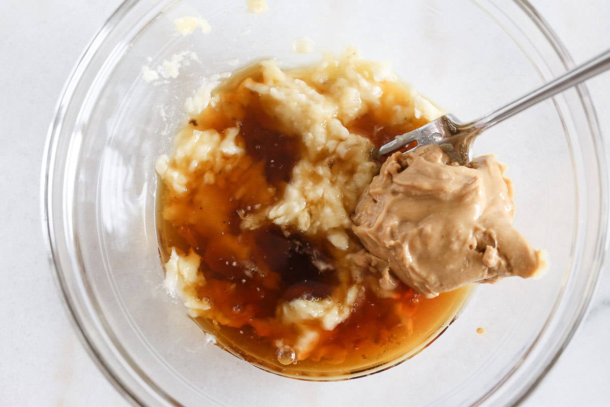 Peanut butter and maple syrup in a glass bowl waiting to be mixed.