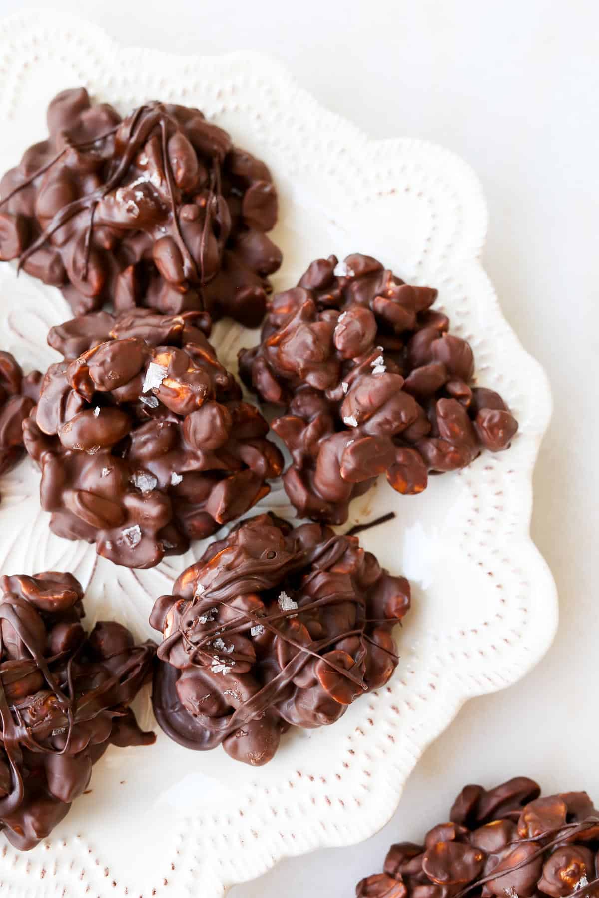 Chocolate Peanut Clusters on a white textures plate.