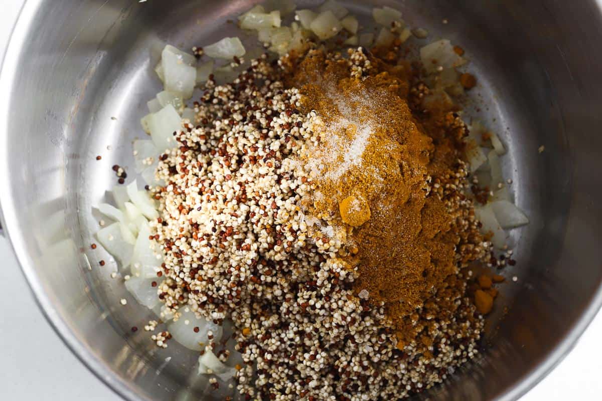 Quinoa and seasonings added to pot with sauteed onion.