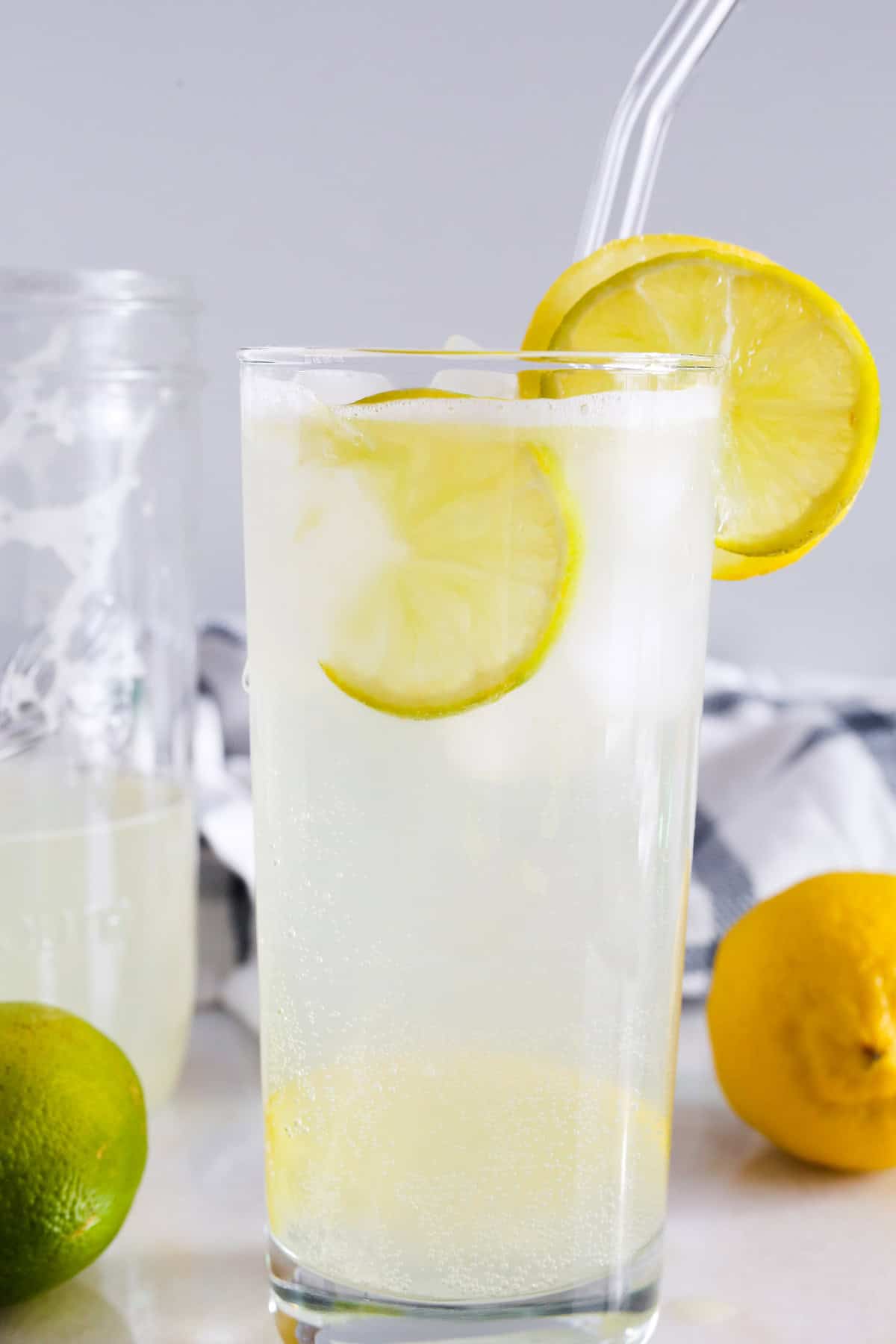 Lemon Lime Spritzer with lemon garnish in a tall clear glass jar with a straw.