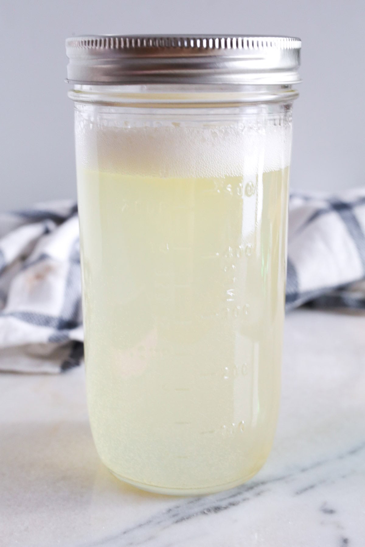 Glass jar with the sparkling water added to the lemon, lime and maple syrup mixture ready to be shaken up.