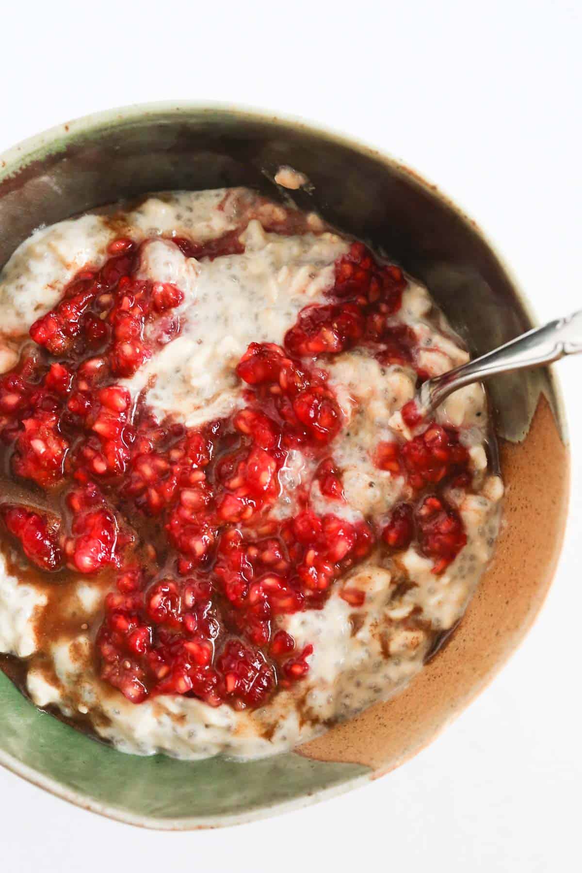 These Raspberry Overnight Oats in a bowl with a spoon sitting on a a marble surface.