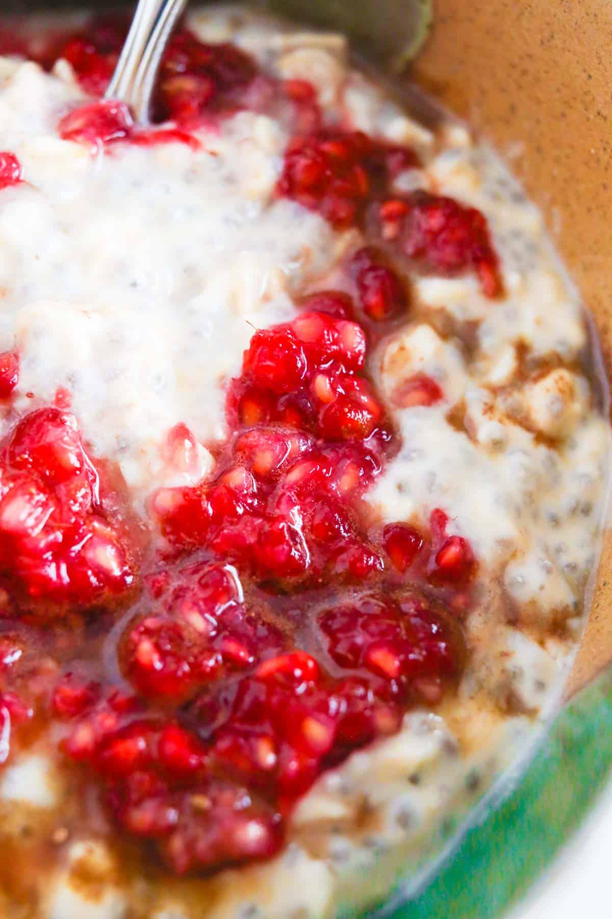 Close up image of These Raspberry Overnight Oats in a bowl topped with mashed raspberries and chocolate.