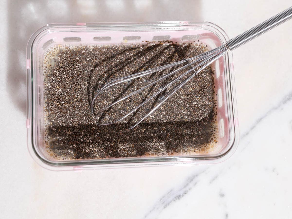 Chia seeds added to container with liquids for this peanut butter chia seed pudding.