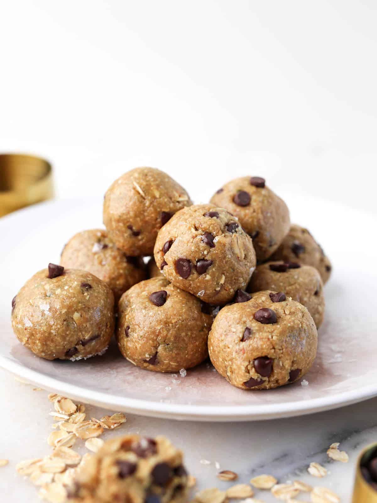 Close up image of these chocolate and peanut butter protein balls on a white plate piled on top each other.