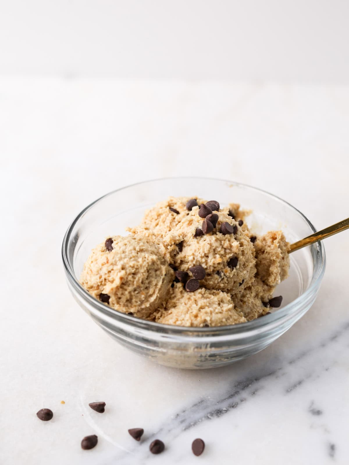 Cookie Dough Yogurt in a small glass bowl with a gold spoon on a marble surface.