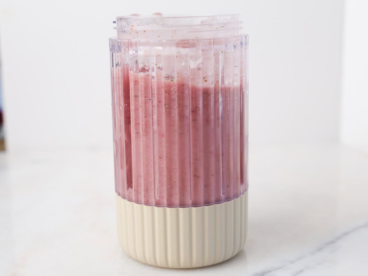 Blended mango smoothie with raspberries.