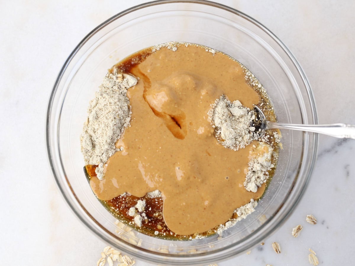 Glass bowl with wet ingredients to make almond butter protein balls.