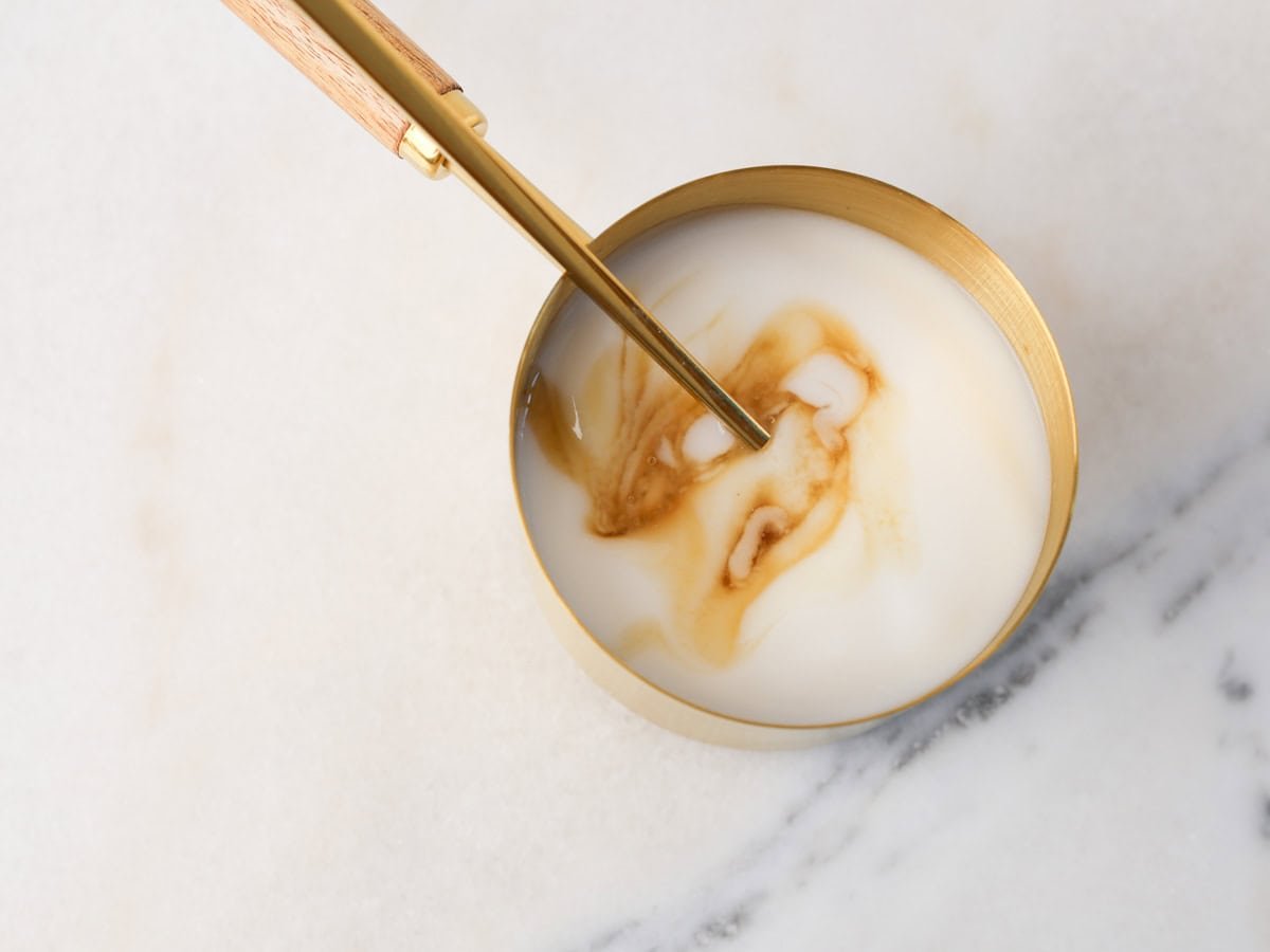 Non-dairy yogurt and maple syrup being mixed together.