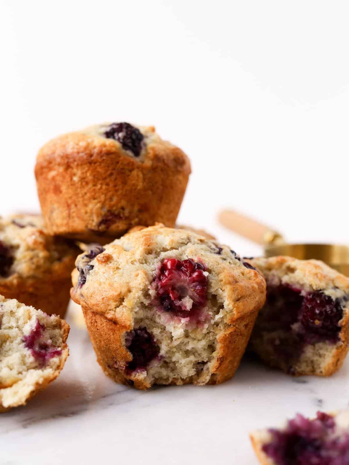 Nice image from the side of this banana blackberry muffin with a big bite taken out of it.