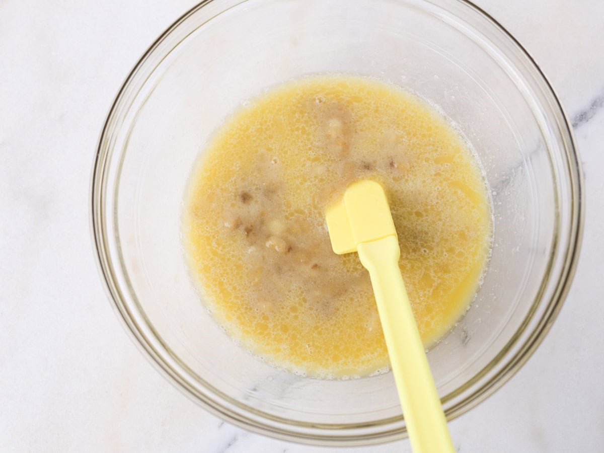 Glass bowl with wet ingredients ttfnbeing mixed to make these banana blackberry oatmeal muffins.