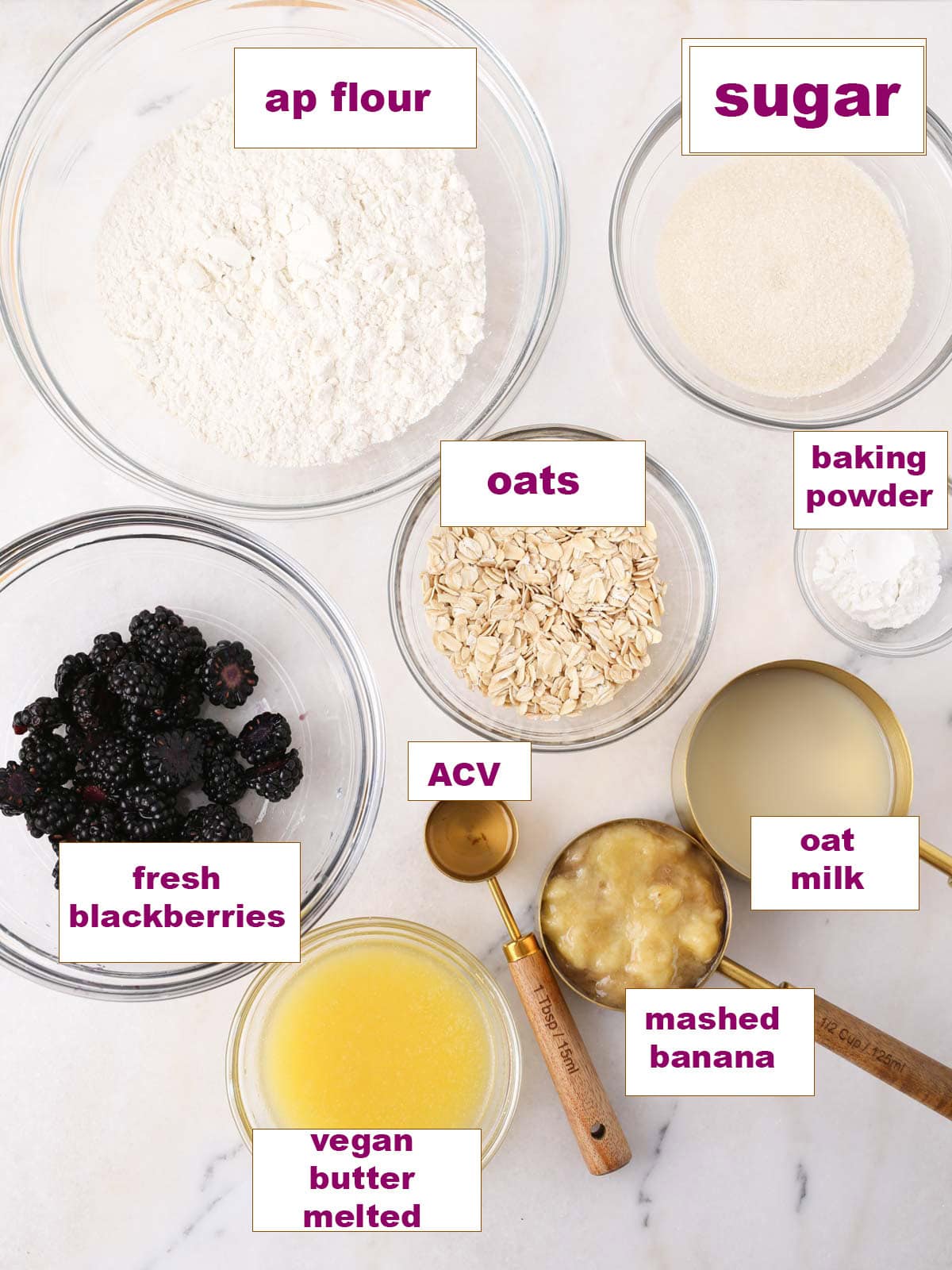 Ingredients in glass bowls set out on marble surface to make these vegan muffins.