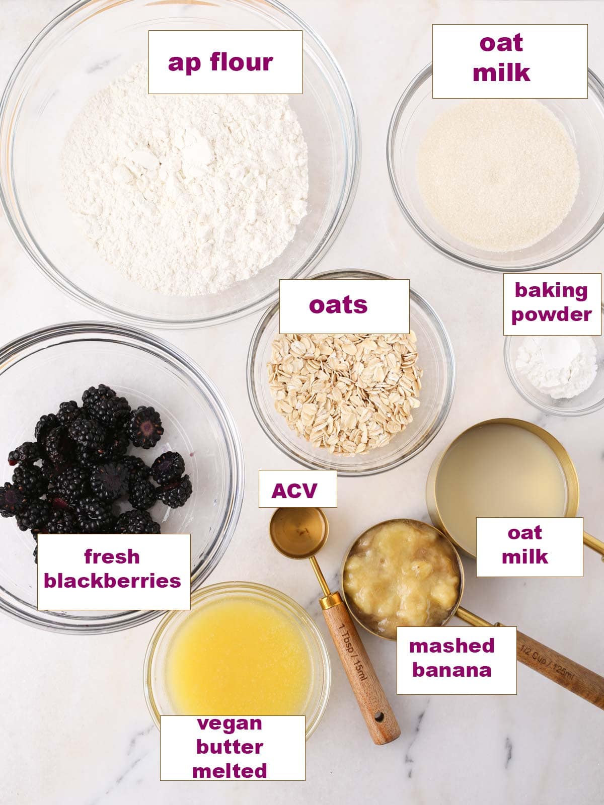 Ingredients in glass bowls set out on marble surface to make these vegan muffins.