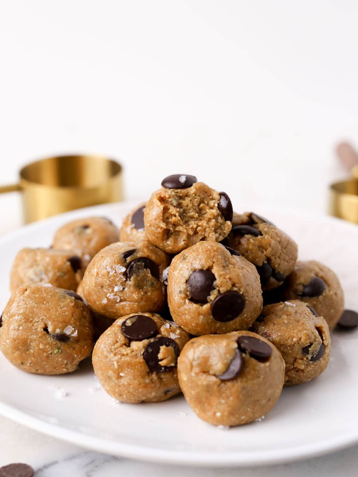 Cookie dough Protein Balls on plate stacked on top each other with bite taken out of top one.