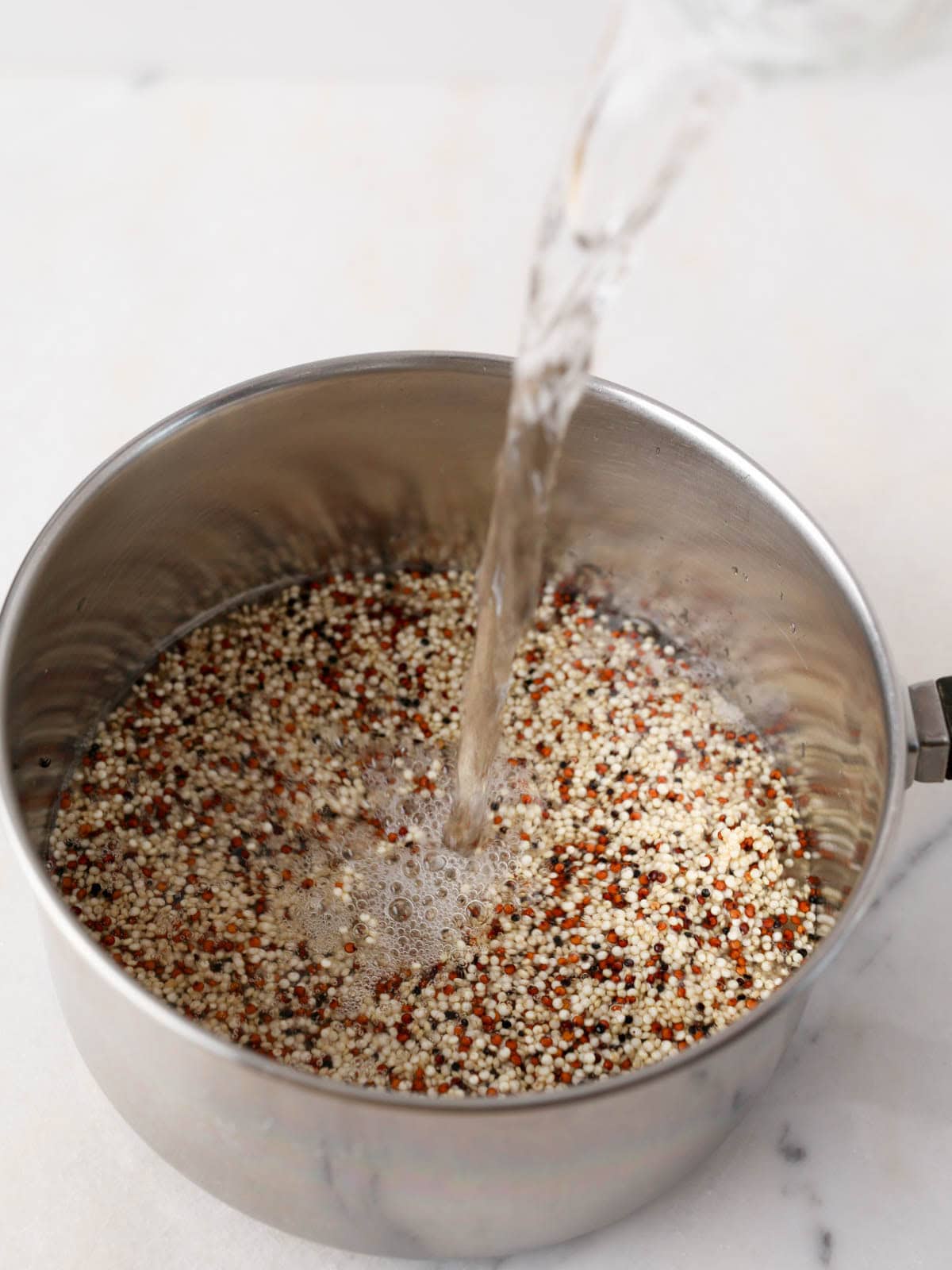 Showing water being add in a pot for how to cook quinoa.