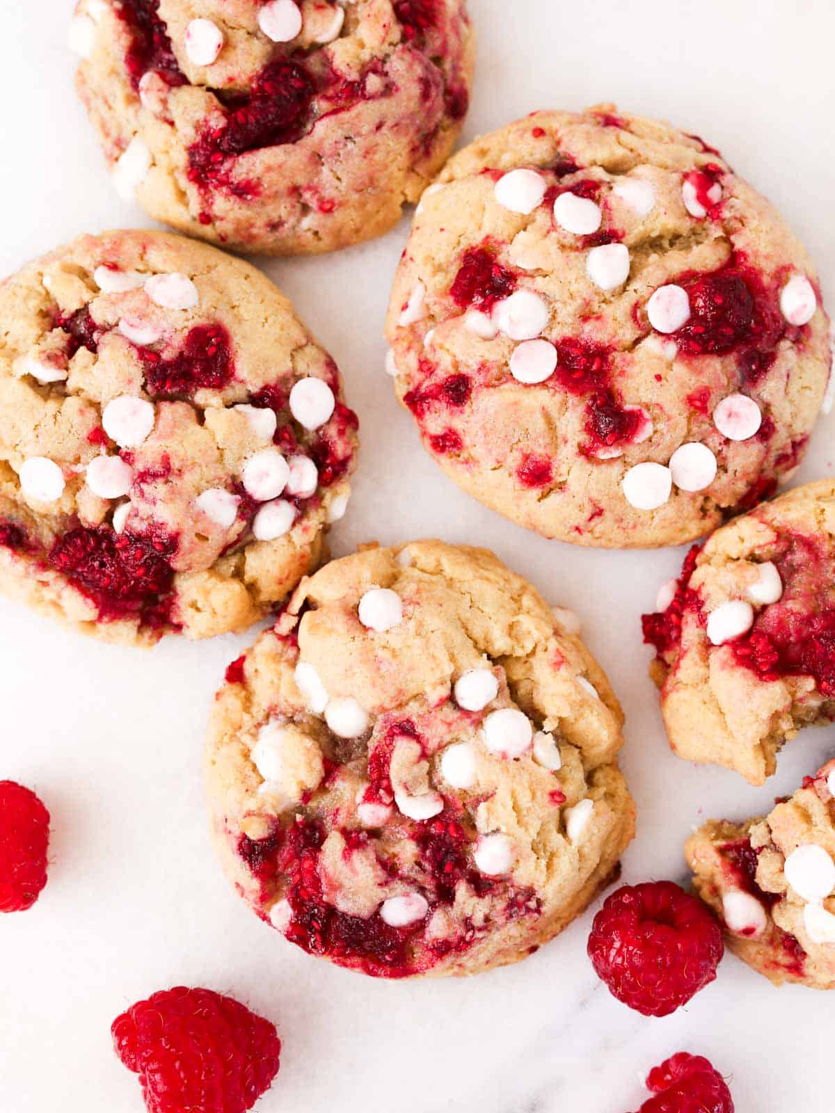 Multiple cookies laying flat, overhead image of cookies with white chocolate and raspberries.