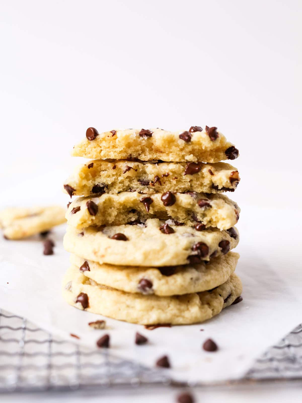 Chocolate chip cookies without brown sugar stacked up tall with top couple broke in half to see the center.