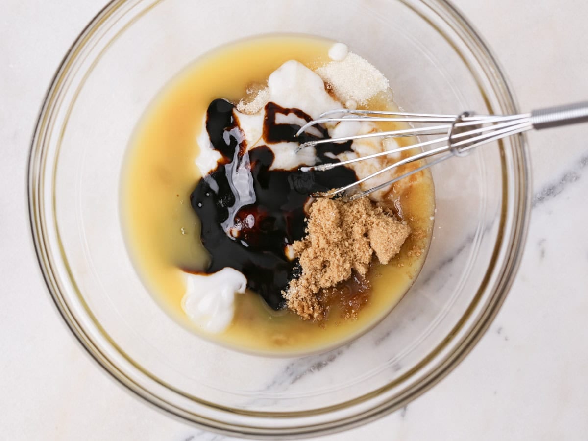 Wet ingredients in glass bowl being whisked.