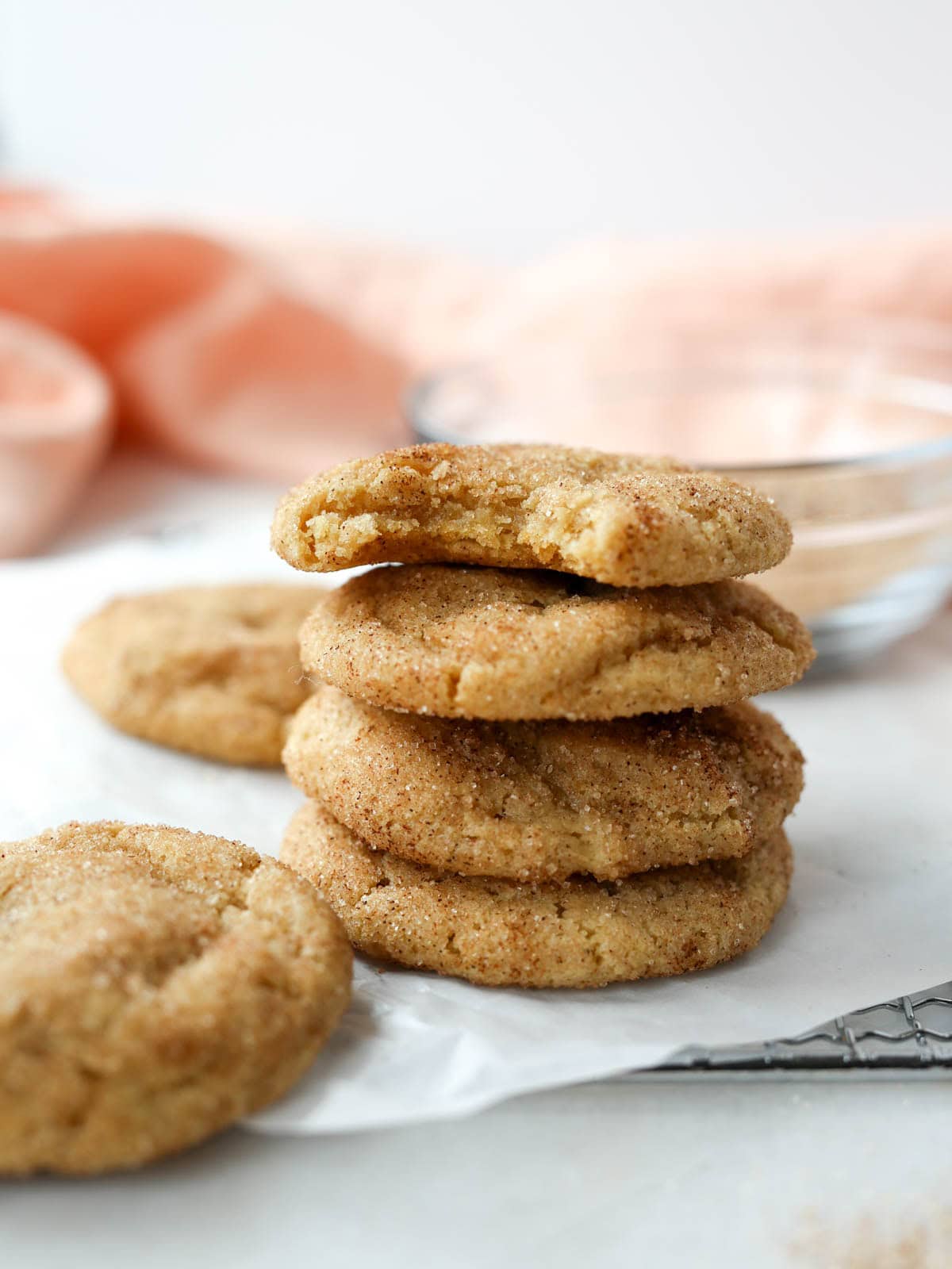 Snickerdoodles stacked on top high with bite taken out of top one.